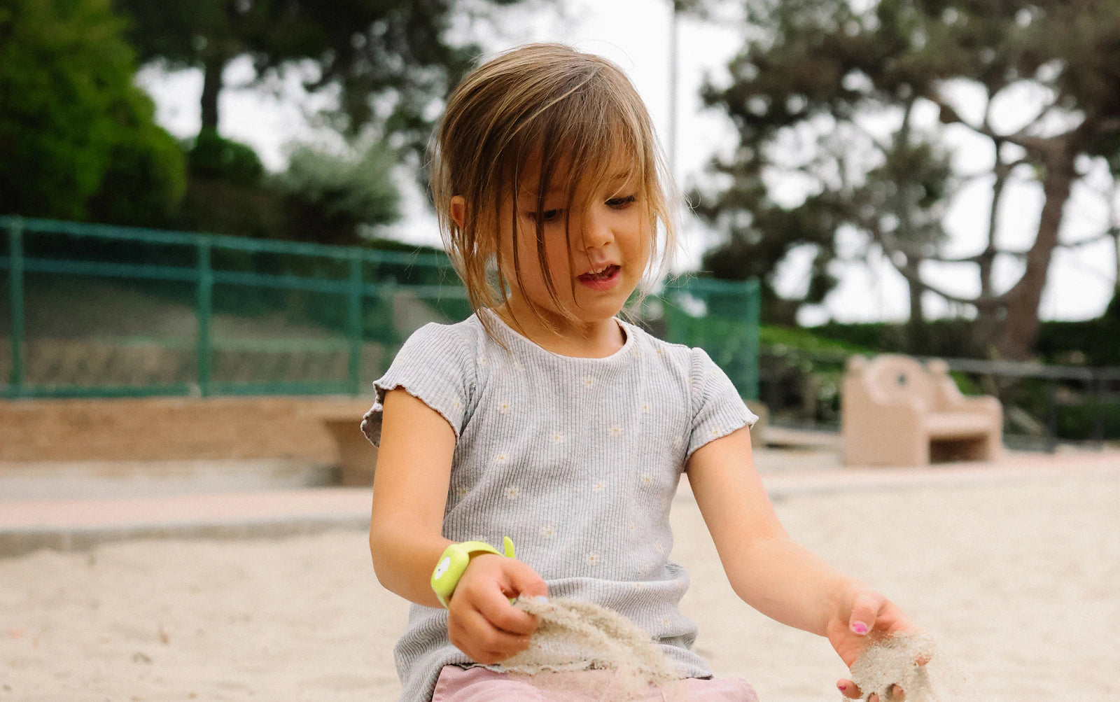 Girl wearing Littlebird tracker playing in sand