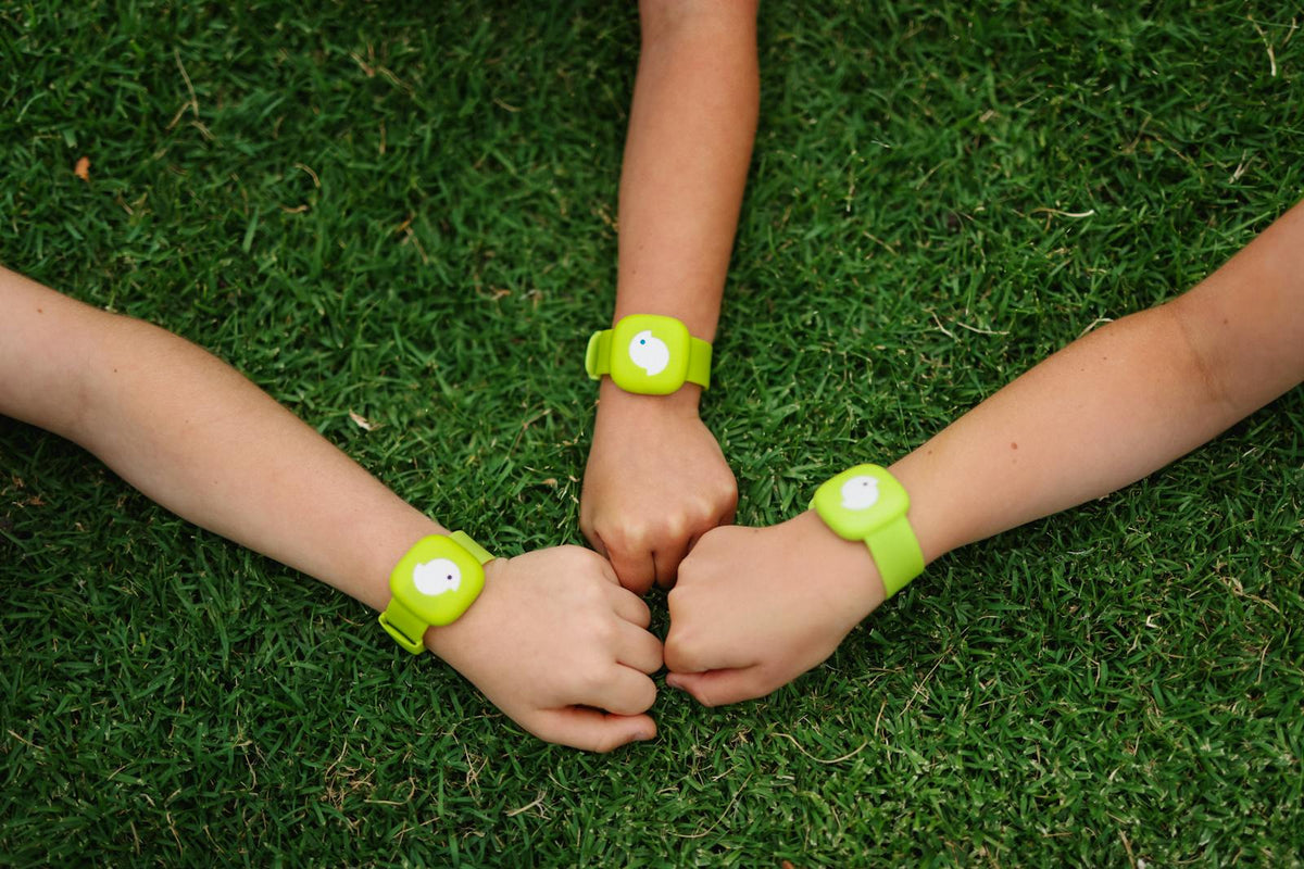 Three kids' wrists wearing green Littlebird bands